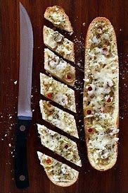 Cheesy bread french loaf sliced w/ knife next to slices